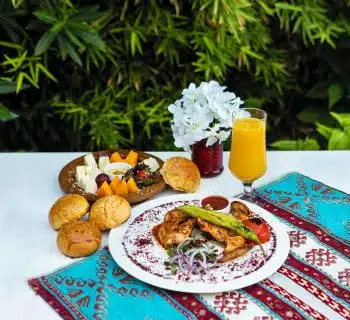 bread with vegetable on white ceramic plate beside drinking glass with yellow liquid